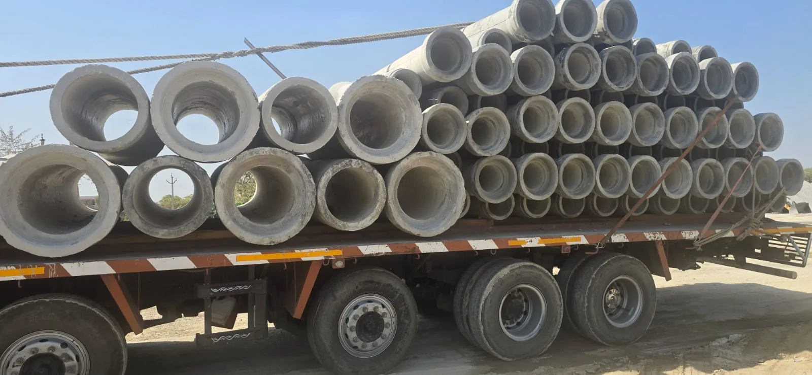 Flatbed trailer loaded with RCC pipes for delivery by Gurukrupa Enterprises